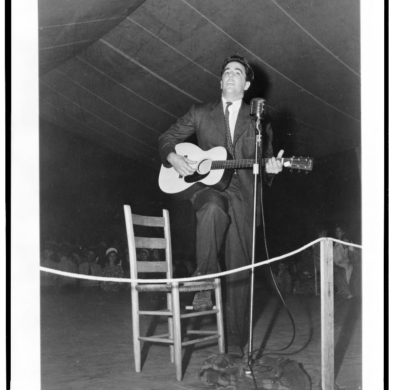 Alan Lomax playing guitar on stage