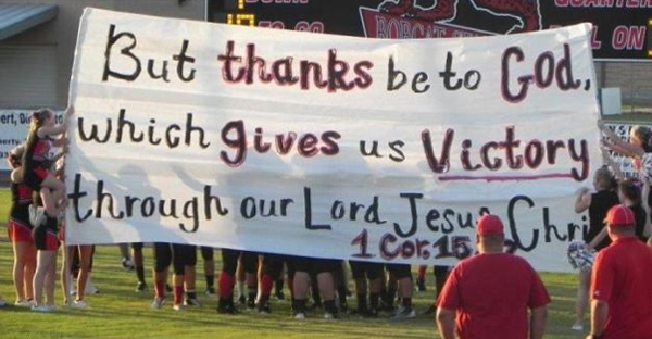banner reads but thanks be to God which gives us our victory