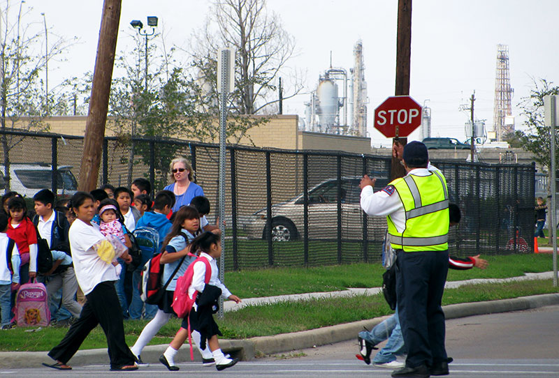Kids crossing the street with chemical plants in the background