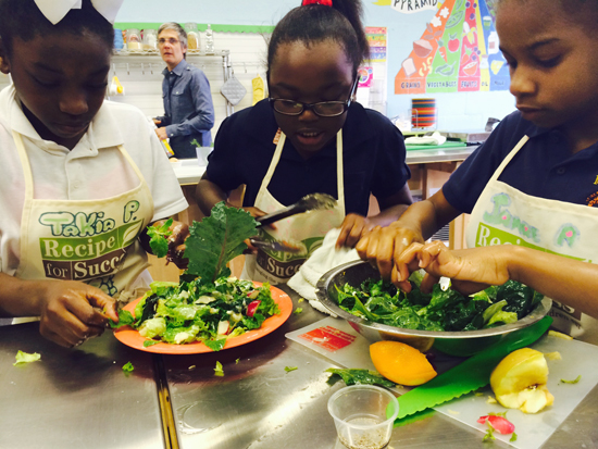 A group of girls mix their salad ingredients. 