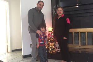 Haider Elias poses near a Christmas tree with his wife and son.