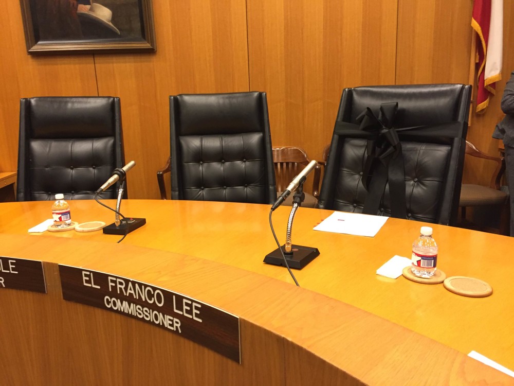 A black ribbon is wrapped around the empty seat of the late Precinct 1 Commissioner El Franco Lee.