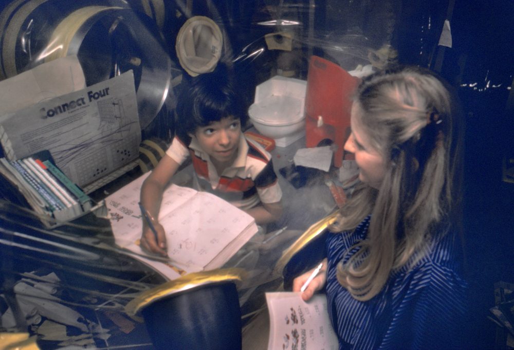 David works with a teacher from inside his isolator, also called his "bubble," in 1979. (Photo Credit: Baylor College of Medicine)