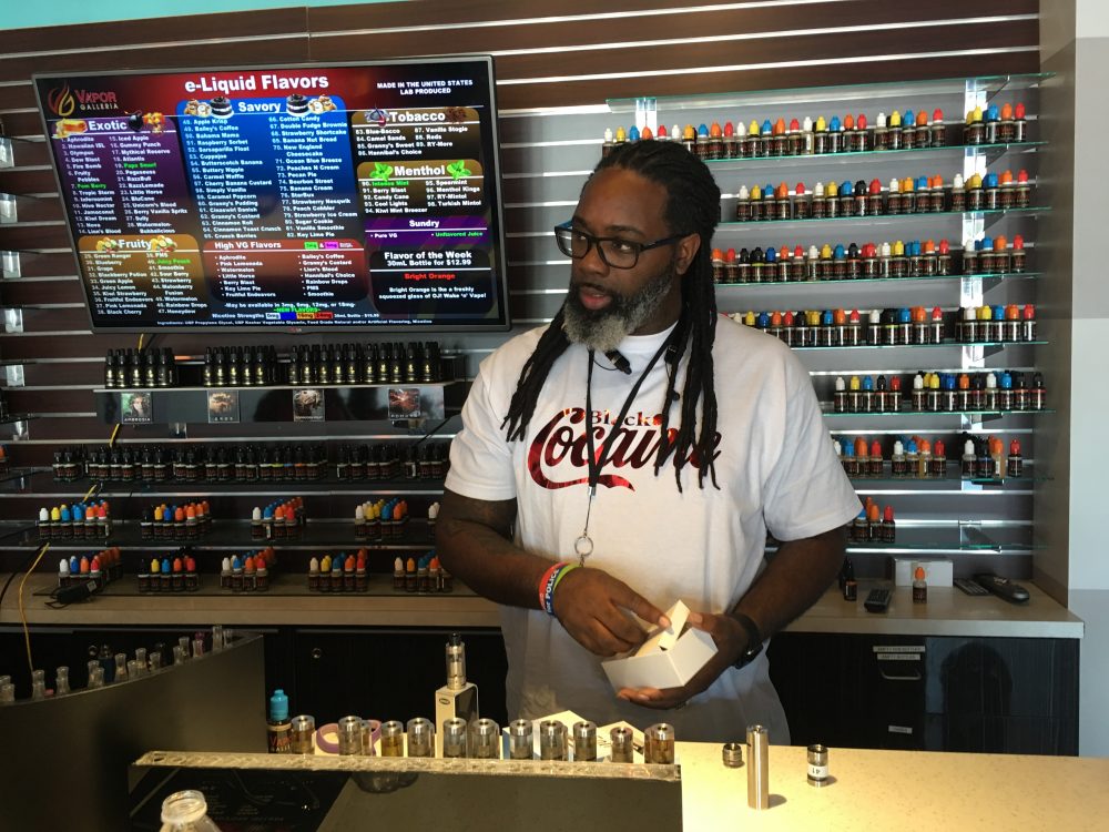 Owner Erick Jones helps customers pick out flavored nicotine fluids at the Vapor Galleria on South Loop West.