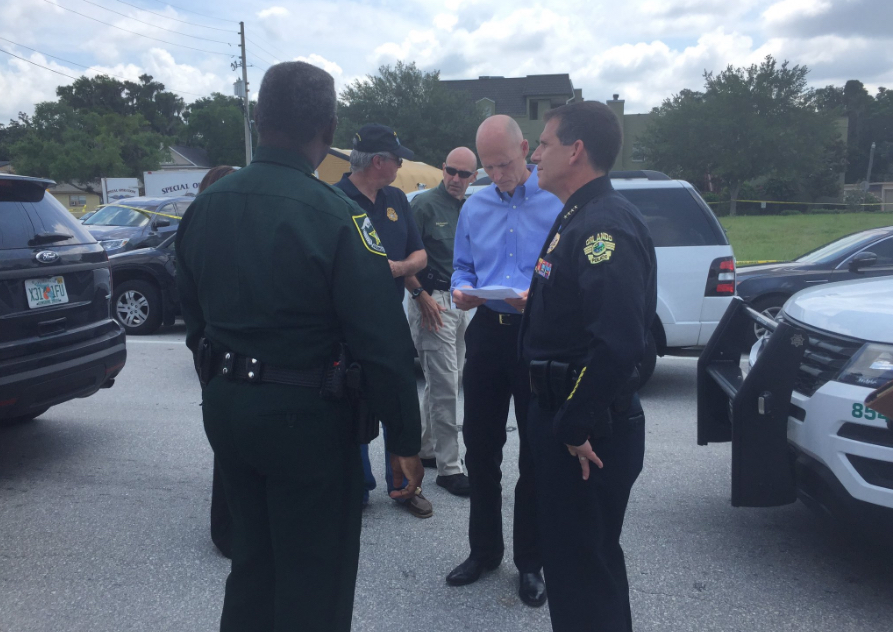 Florida Gov. Rick Scott talks with law enforcement before a briefing about the Sunday morning shooting at Pulse nightclub in Orlando.
