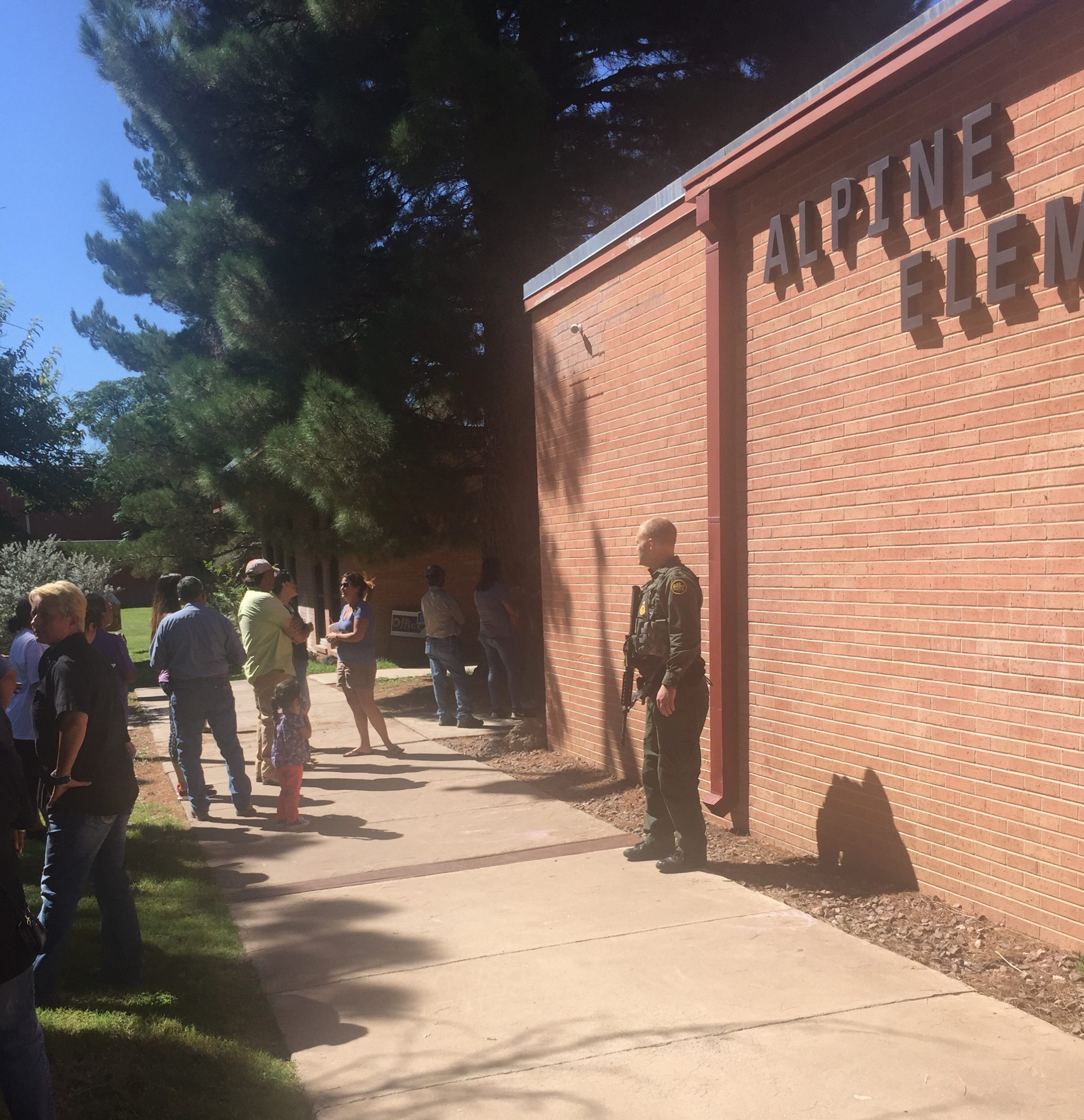 A Border Patrol agent keeps watch as parents arrive to take their children home from Alpine Elementary School after Thursday's shooting at nearby Alpine High School. 