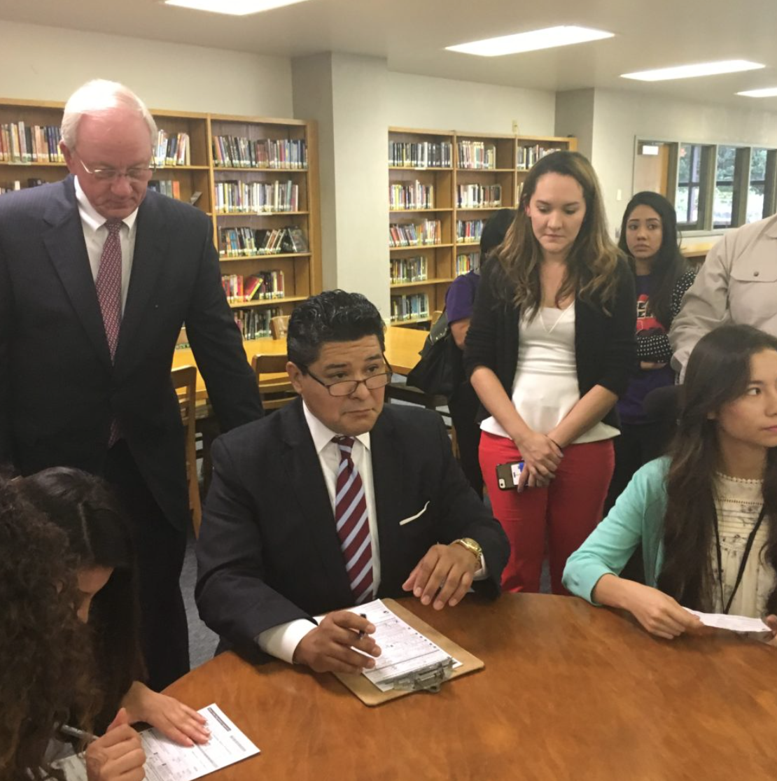 Richard Carranza, Houston ISD Superintendent, a recent arrival from California, registers as a Texas voter alongside students at Sam Houston Math, Science, and Technology Center. Mike Sullivan, Harris County Tax Assessor-Collector, looks on.