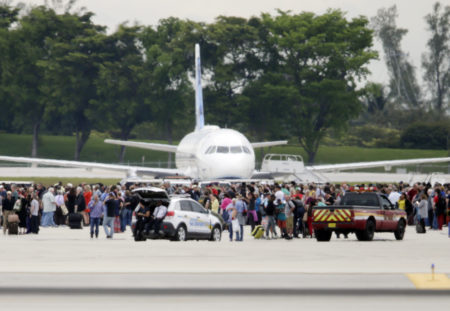People stand on the tarmac at the Fort Lauderdale-Hollywood International Airport in Florida after a shooter opened fire inside a terminal, killing at least five people and wounding eight others before being taken into custody Friday