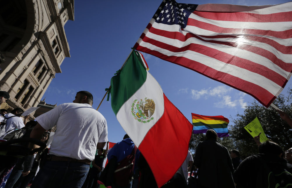 A man hold the U.S and Mexico flags during a march and rally during an immigration protest, Thursday, Feb. 16, 2017, in Austin, Texas. Immigrants around the U.S. stayed home from work and school Thursday to demonstrate how important they are to America's economy and its way of life, and many businesses closed in solidarity, in a nationwide protest called A Day Without Immigrants. 