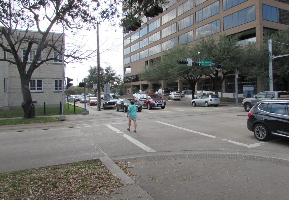 A pedestrian crosses San Jacinto at Binz Street in Houston's Museum District