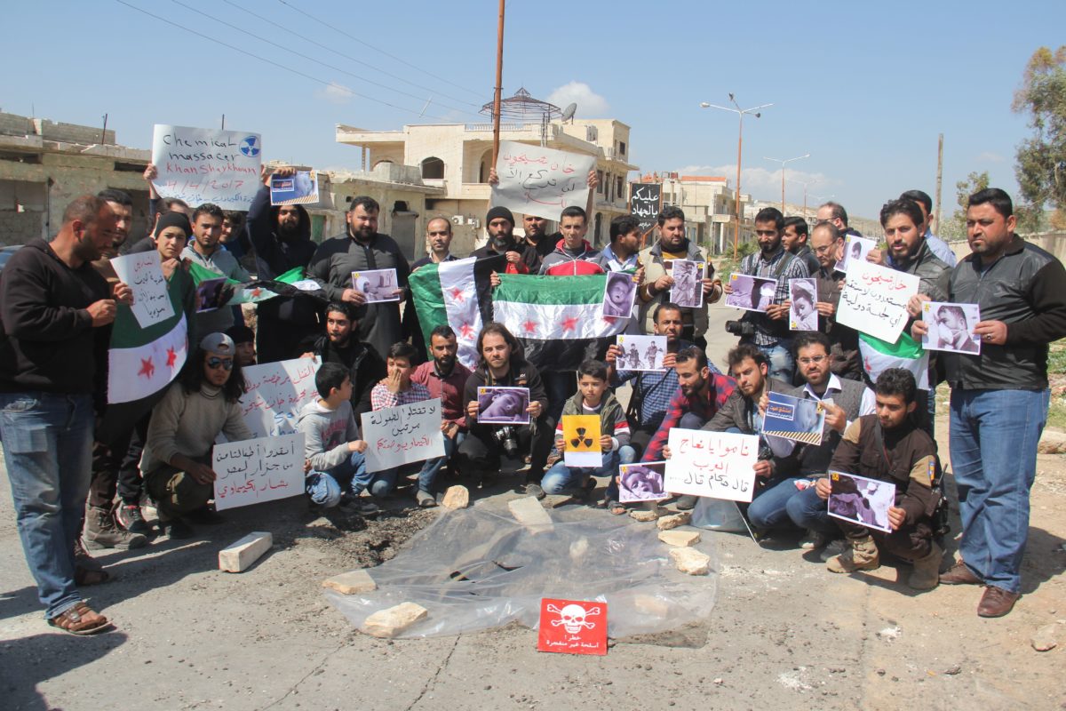Syrian residents of Khan Shaykhun hold signs and pictures on Friday during a protest condemning a suspected chemical weapons attack on their town earlier this week.