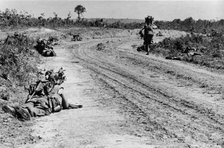 U.S. Marines of the 2nd Battalion lie in the dirt alongside Road 561 as one of them is running around the curve to get into better fireposition, near Cam Lo, South Vietnam, May, 19, 1967.