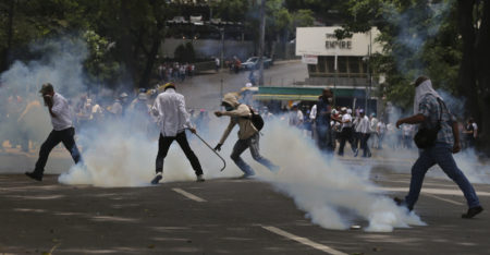 Demonstrators run for cover from tear gas launched by security forces during an anti-government protest in in Caracas, Venezuela, Wednesday, April 19, 2017. Opponents of President Nicolas Maduro called on Venezuelans to take to the streets in marched against the embattled socialist leader. Government supporters are holding their own counter demonstration. (AP Photo/Fernando Llano)