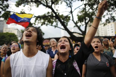 A woman, center, cries as she sings during an homage to Juan Pablo Pernalete in Caracas, Venezuela, Thursday, April 27, 2017. Pernalete, the latest victim of Venezuela's unrest, was killed during anti-government protests Wednesday when he was struck by a tear gas canister fired by security forces. (AP Photo/Ariana Cubillos)