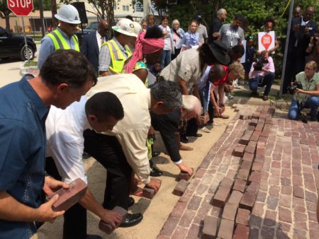 Preservationists and city officials lay the last of the misplaced bricks on Andrews Street.