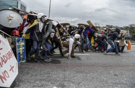 Hooded demonstrators equipped with helmets, gas masks and makeshift shields face off against riot police during a protest in Venezuela's capital, Caracas, on Wednesday.