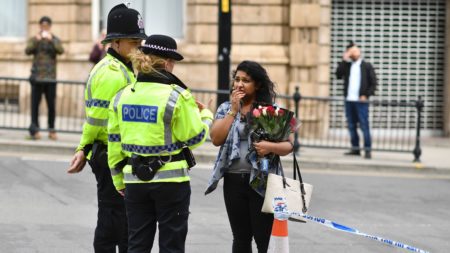A woman speaks with police officers after bringing flowers close to the area where a bombing struck outside the Manchester Arena Monday night.