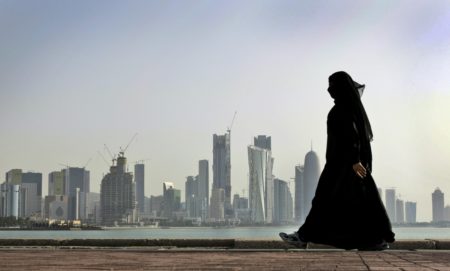 FILE- In this May 14, 2010 file photo, a Qatari woman walks in front of the city skyline in Doha, Qatar. A popular independent online news outlet in the Gulf nation of Qatar says its website has been blocked inside the country. The Doha News site said Thursday that Qatar's two internet service providers simultaneously blocked the site, suggesting they did so on order of government regulators. (AP Photo/Kamran Jebreili, File)