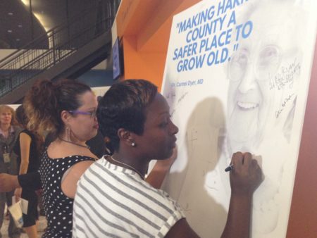 Monica Lara and Malishia Janice sign a pledge displayed after an event to officially announce the Harris County Senior Justice Assessment Center.
