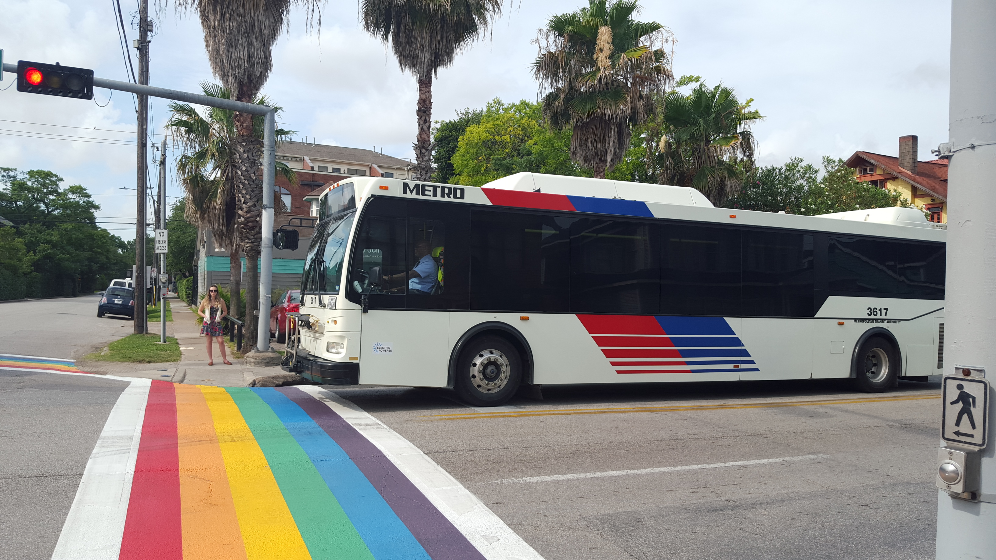 A METRO bus and a pedestrian at the rainbow crosswalk in Montrose.