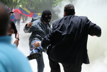 A masked men kicks at opposition lawmaker Franco Casella in a melee with pro-government militias who tried to forced their way into the National Assembly during a special session coinciding with Venezuela’s independence day, in Caracas, Wednesday, July 5, 2017. At least five lawmakers were injured in the attack. (AP Photos/Fernando Llano)
