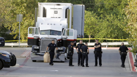 San Antonio police officers are seen in a parking lot where eight people were found dead in a tractor-trailer that contained at least 30 others outside a Walmart store.