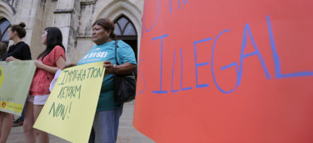 Eldia Contreras, right, and others hold a signs as they take part in a vigil at San Fernando Cathedral for victims who died as a result of being transported in a tractor-trailer, Sunday, July 23, 2017, in San Antonio. At least nine people died after being crammed into a sweltering tractor-trailer found parked outside a Walmart in the midsummer Texas heat, authorities said Sunday in what they described as an immigrant-smuggling attempt gone wrong. (AP Photo/Eric Gay)