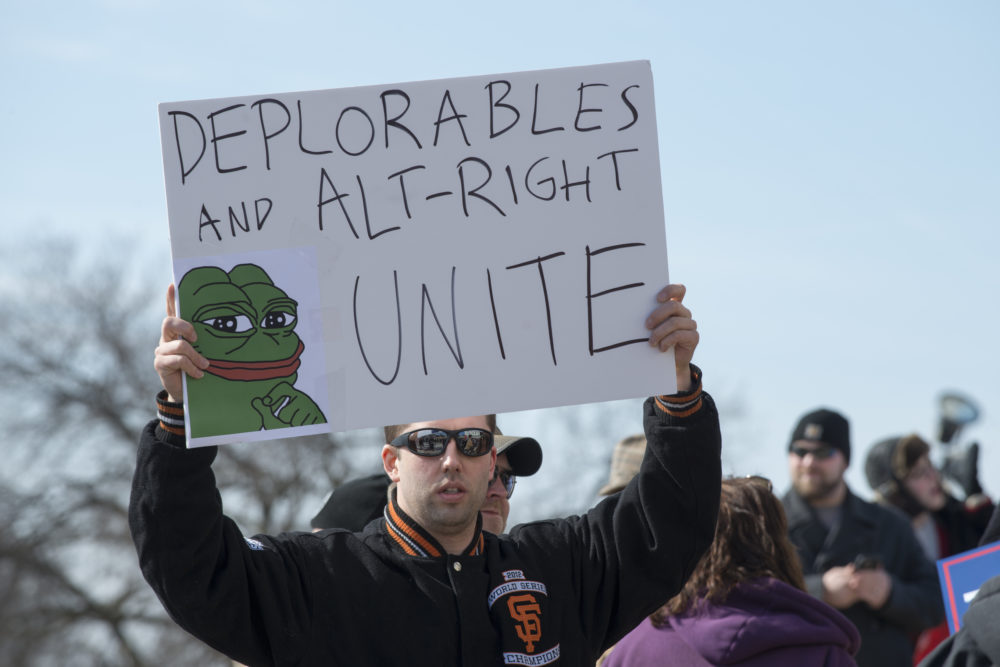 A Trump supporter holding up a sign reading "Deplorables and Alt-Right Unite," including an image of Pepe the Frog. The cartoon character has become a symbol for white supremacist groups.
