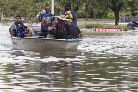 Evacuees flee flooding in a boat with a nearly submerged Houston sign behind them, on Aug, 29, 2017.
