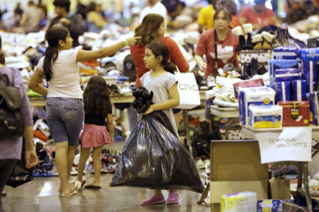 A Harvey flood evacuated child carries donated supplies in a trash bag at a shelter setup inside NRG Center, Wednesday, Aug. 30, 2017, in Houston. (AP Photo/David J. Phillip)