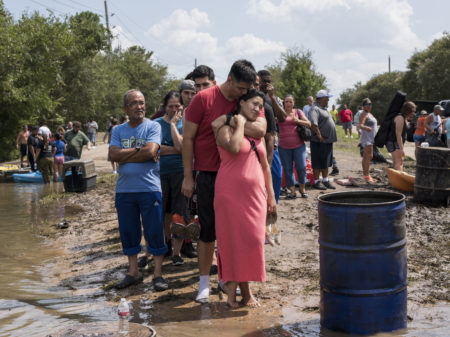 Ellie Nizamutdinova is comforted by her partner, Arnulfo Moreno, while they wait in line for a boat ride to check on their flooded home along Barker Cypress road on the west side of Houston.