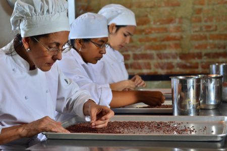 Entrepreneurs sort cocoa beans on a tray at Cacao de Origen, a school founded by Maria Di Giacobbe to train Venezuelan women in the making of premium chocolate. Zeina Alvarado (left) later found work in a bean-to-bar production facility in Mexico