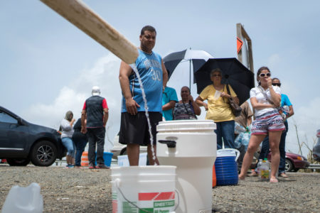 People fill containers with water from a stream near the Puerto Rico Highway 52 in Cayey on Tuesday. People have been without water service in their homes after Hurricane Maria roared through a week ago.