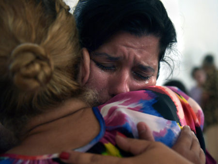 Ada Reyes weeps and hugs Johanna Nieves Diaz as people comfort one another during the church service. "I forget about everything going on in the street for a little bit, at least," Reyes said.