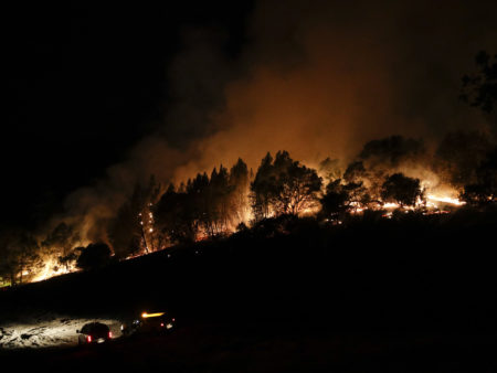 Firefighters watch from their fire trucks as wildfires continue to burn on Thursday, near Calistoga, Calif.