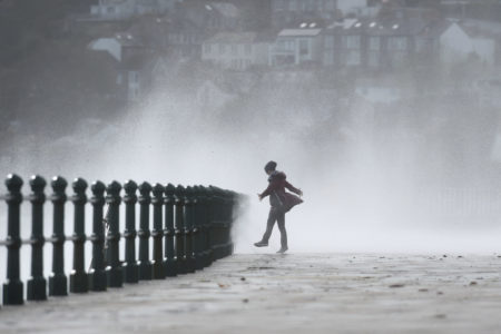 A woman stands as waves crash against the sea wall at Penzance, southwestern England, as the remnants of Ophelia begin to hit parts of the U.K. and Ireland.