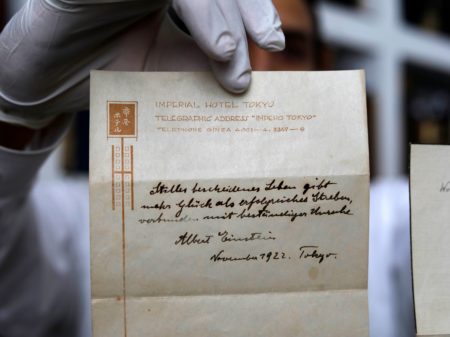 The owner of a Jerusalem auction house holds up a note on happiness written by Albert Einstein in 1922. The note, which Einstein gave to a courier in lieu of a tip, sold for $1.56 million on Tuesday to an anonymous buyer.