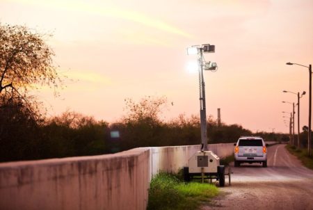 At sunset, a Customs and Border Patrol agent places floodlights along a levee that ties into a segment of border fence in Hidalgo, Texas.