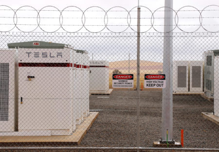 Warning signs adorn the fence surrounding the compound housing the Hornsdale Power Reserve, featuring the world's largest lithium ion battery made by Tesla, during the official launch near Jamestown, Australia, on Friday.