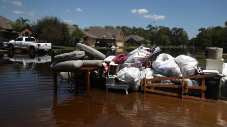 Damaged furniture and personal belongings sit in front of a flooded home in September in Richwood, Texas. Several months after Hurricane Harvey hit southern Texas, residents are still navigating the long recovery process.