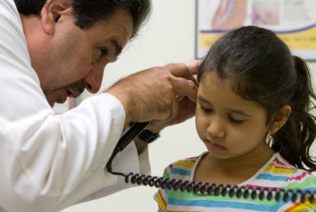 Dr. Javier Saenz checks the ear of Viviana Escareño, 6, for infection. The young girl’s mother, Claudia Escareño, has brought “Vivi” to Saenz’s clinic since she was born.