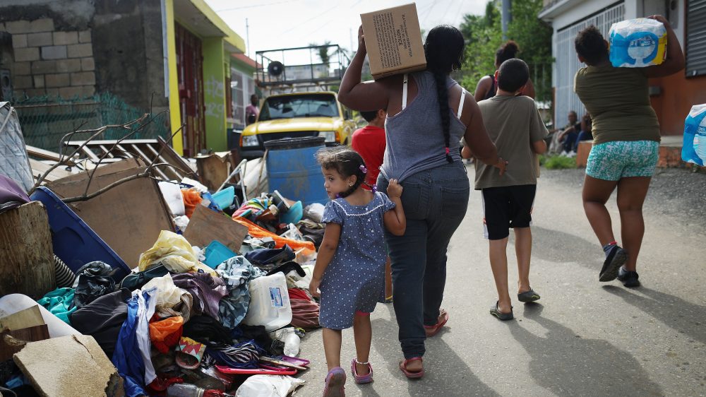 Residents of San Isidro, Puerto Rico, carry food and water provided by FEMA to a neighborhood without electricity or running water last October.