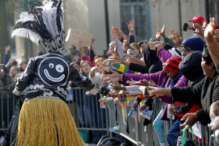 A member of the Krewe of Zulu hands out coconuts to the crowd as their parade rolls on Mardi Gras day in New Orleans, Tuesday, Feb. 13, 2018. (AP Photo/Gerald Herbert)