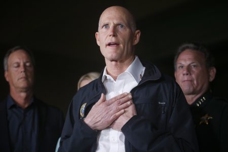 Florida Gov. Rick Scott gestures as he speaks during a news conference near Marjory Stoneman Douglas High School in Parkland, Fla., where a former student is suspected of killing at least 17 people Wednesday, Feb. 14, 2018. The shooting at a South Florida high school sent students rushing into the streets as SWAT team members swarmed in and locked down the building. Police were warning that the shooter was still at large even as ambulances converged on the scene and emergency workers appeared to be treating those possibly wounded. (AP Photo/Wilfredo Lee)