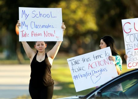 Angelina Lazo (L), an 18-year-old senior at Marjory Stoneman Douglas High School, who said that she lost two friends in the shooting at her school two days ago, reacts to honks of support from passing motorists as she and her mother, Linda Lazo, right, join other gun control proponents with placards at a street corner in Coral Springs, Florida, U.S. February 16, 2018.