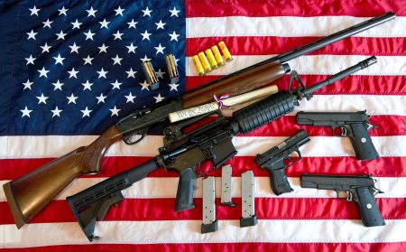 A Remington 20-gauge semi-automatic shotgun, a Colt AR-15 semi-automatic rifle, a Colt .45 semi-auto handgun, a Walther PK380 semi-auto handgun and ammunition set against an American flag.