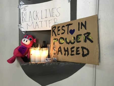 A makeshift memorial for Saheed Vassell, 34, stands Thursday in the lobby of the apartment building that neighbors identified as his father's residence.
