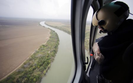 In this Tuesday, Feb. 24, 2015, aerial file photo, a U.S. Customs and Border Protection Air and Marine agent looks out along the Rio Grande on the Texas-Mexico border in Rio Grande City, Texas. U.S. Homeland Security Secretary Kirstjen Nielsen said Wednesday, April 4, 2018, that President Donald Trump and border-state governors are working to “immediately” deploy the National Guard to the U.S.-Mexico border to fight illegal immigration.