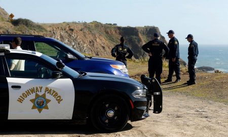 In this March 28, 2018, file photo, California Highway Patrol officers and deputy sheriffs from Mendocino and Alameda counties gather after a search for three missing children at the site where the bodies of Jennifer and Sarah Hart and three of their adopted children were recovered two days earlier, after the family's SUV plunged over a cliff at a pullout on the Pacific Coast Highway near Westport, Calif.