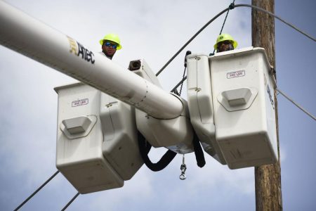 In this Thursday, Oct. 19, 2017 photo, a brigade from the Electric Power Authority repairs distribution lines damaged by Hurricane Maria in the Cantera community of San Juan, Puerto Rico. The storm struck after the Authority had filed for bankruptcy in July, put off maintenance and had finished dealing with outages from Hurricane Irma.